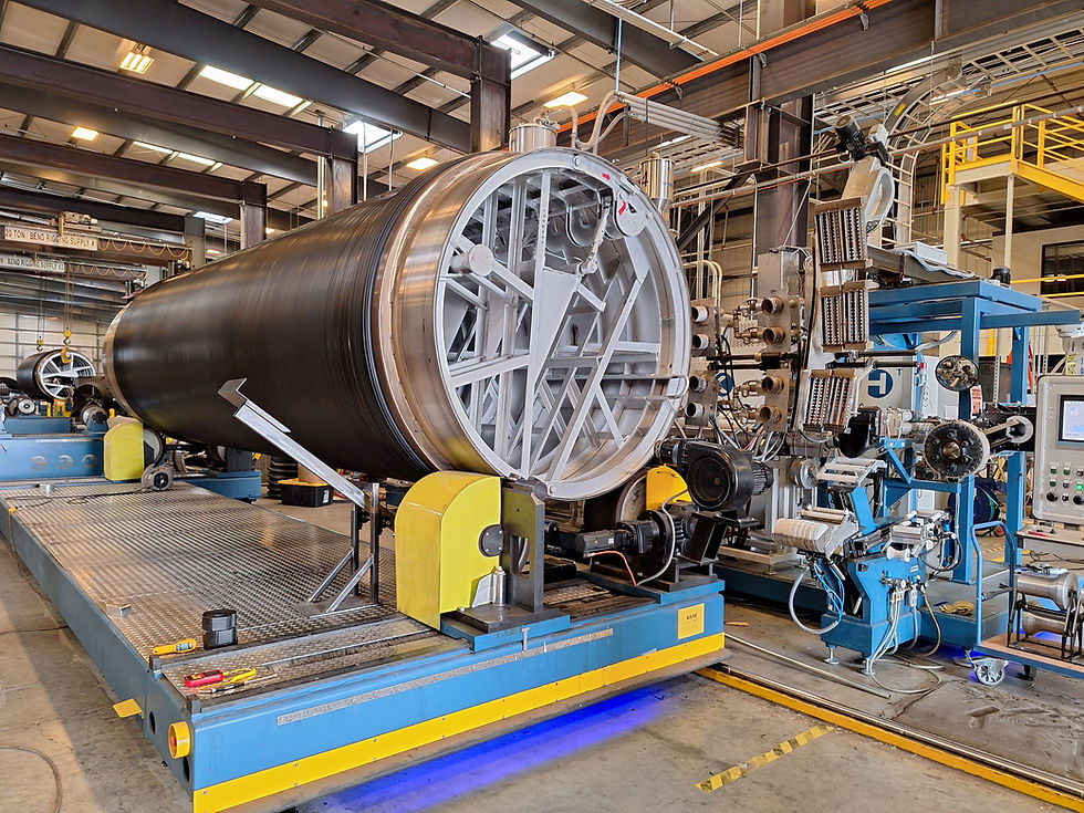 A cluster of large industrial pipes arranged in a complex network against a neutral background.