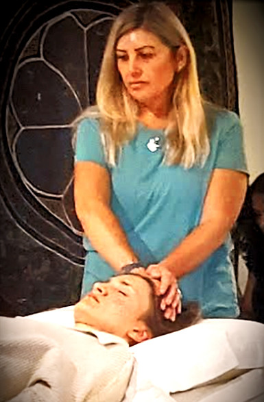 A woman practicing Reiki, gently placing her hands above a seated recipient’s shoulders, channeling calming energy.