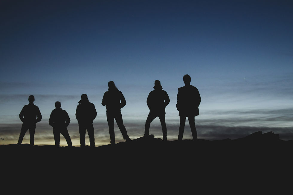 Silhouettes of six people standing on a hill at dusk