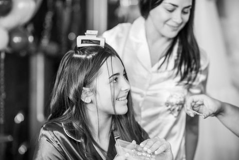 A smiling girl having her hair styled during wedding preparations