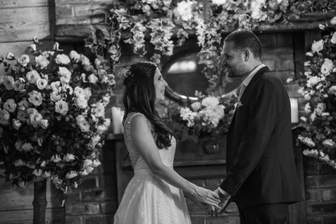 Holding hands beside the floral backdrop — ROB and LOUISE wedding