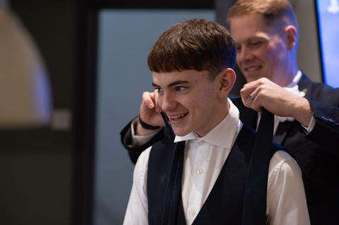 A young wedding guest having his tie adjusted