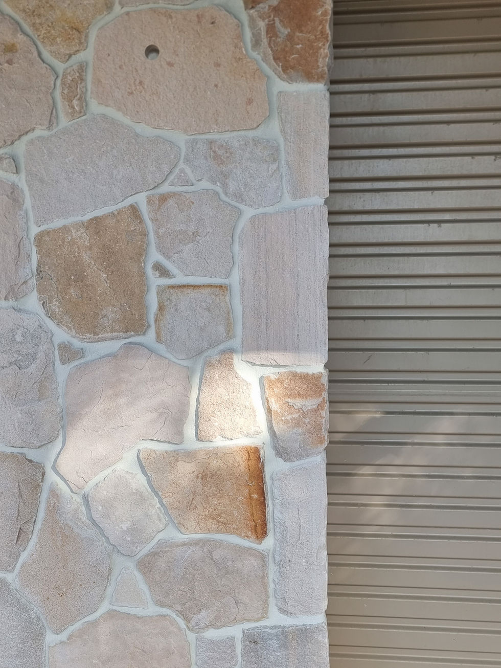 Natural stone cladding wall beside a metal shutter door, Lennox Heads NSW