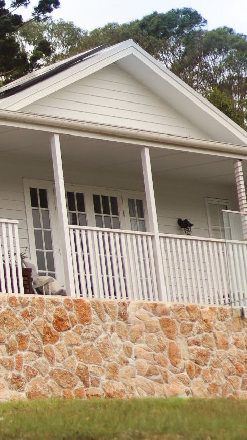 White house with porch and natural stone cladding foundation, Clothiers Creek NSW