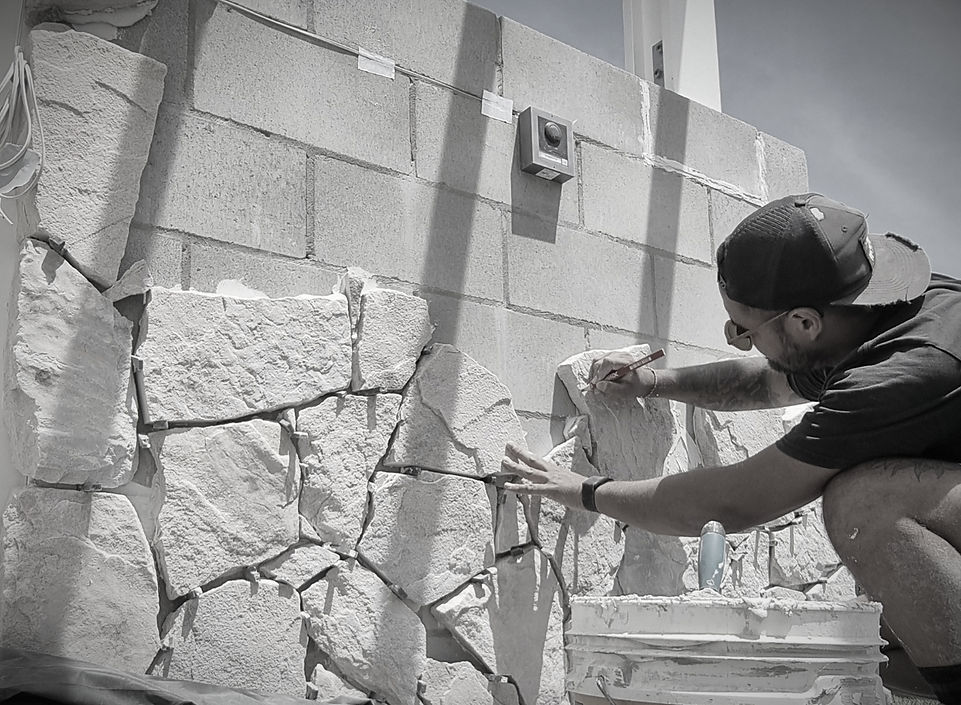 Stonemason hand-carving natural stone for a custom feature wall