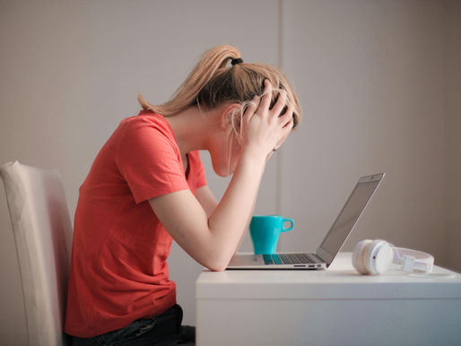 A woman with her head in her hands looking at a computer