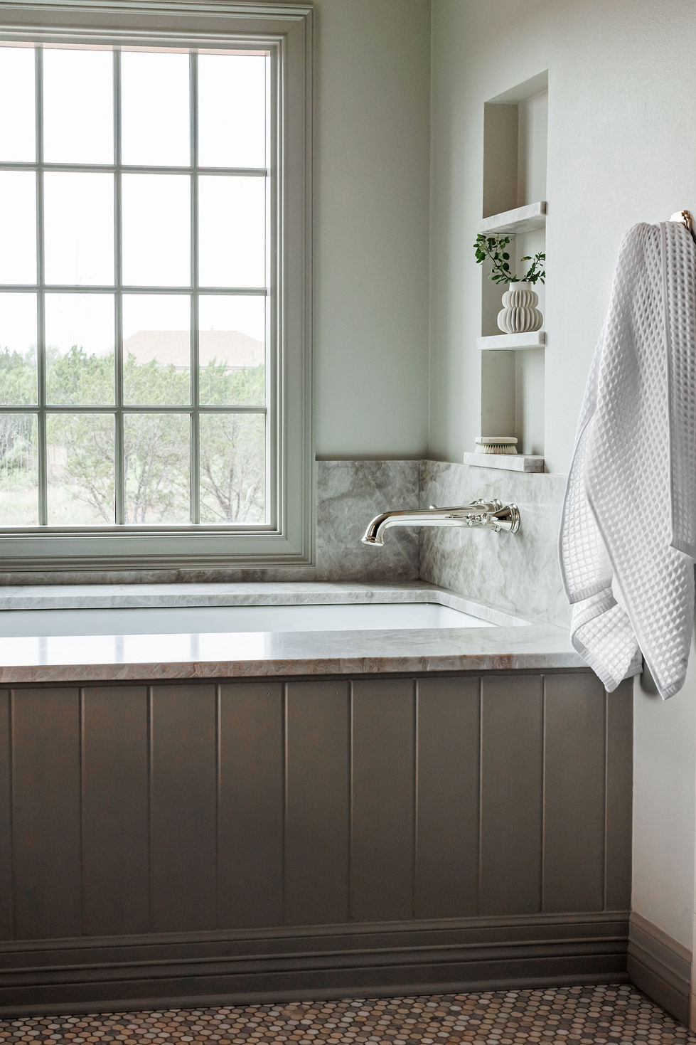 Cozy bathroom with a bathtub and large window.