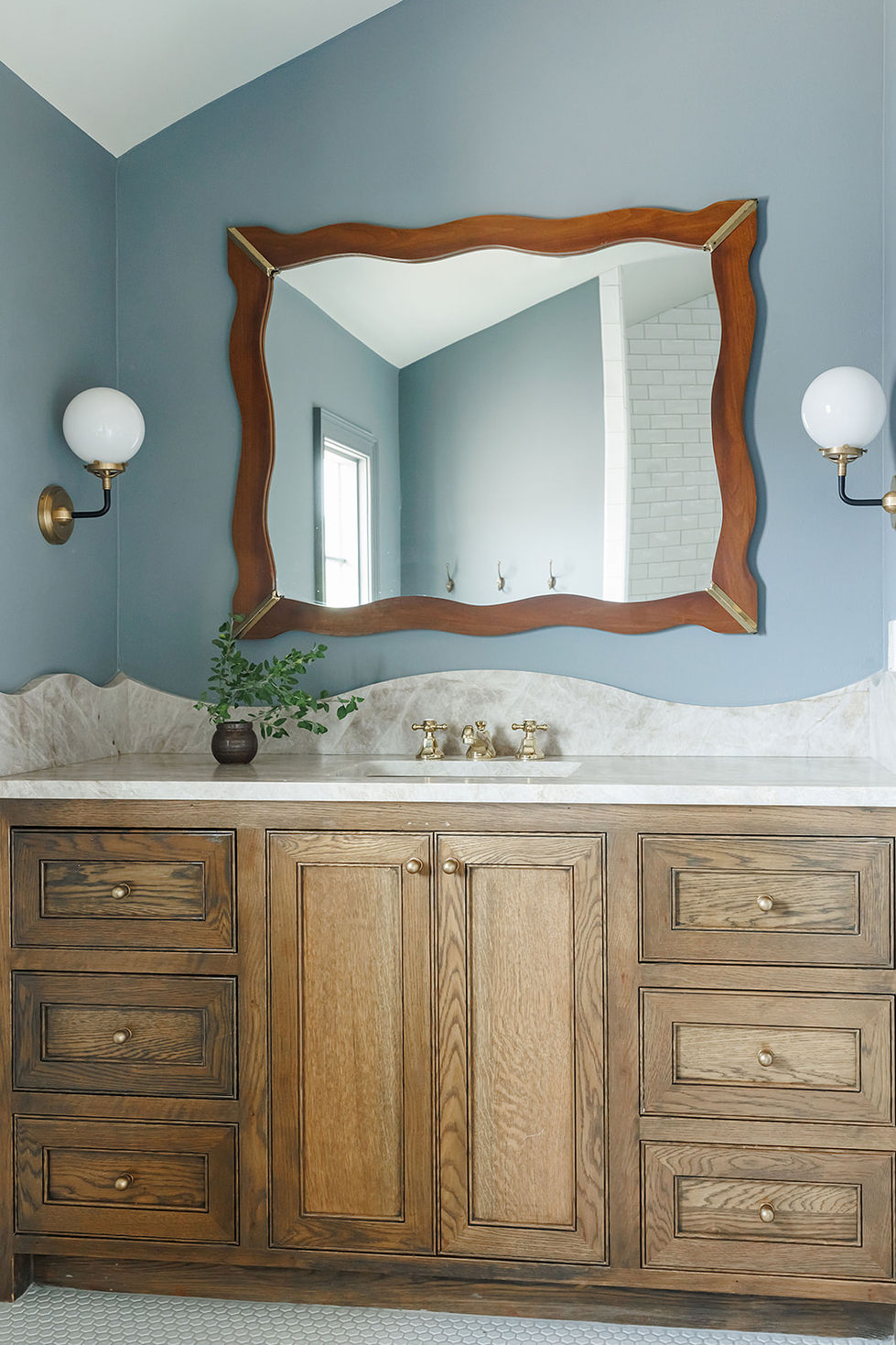 Bathroom vanity with wooden cabinets and ornate mirror.