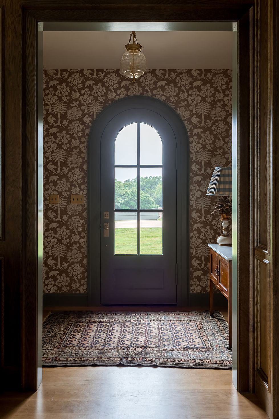 Ornate hallway with arched door and patterned wallpaper.