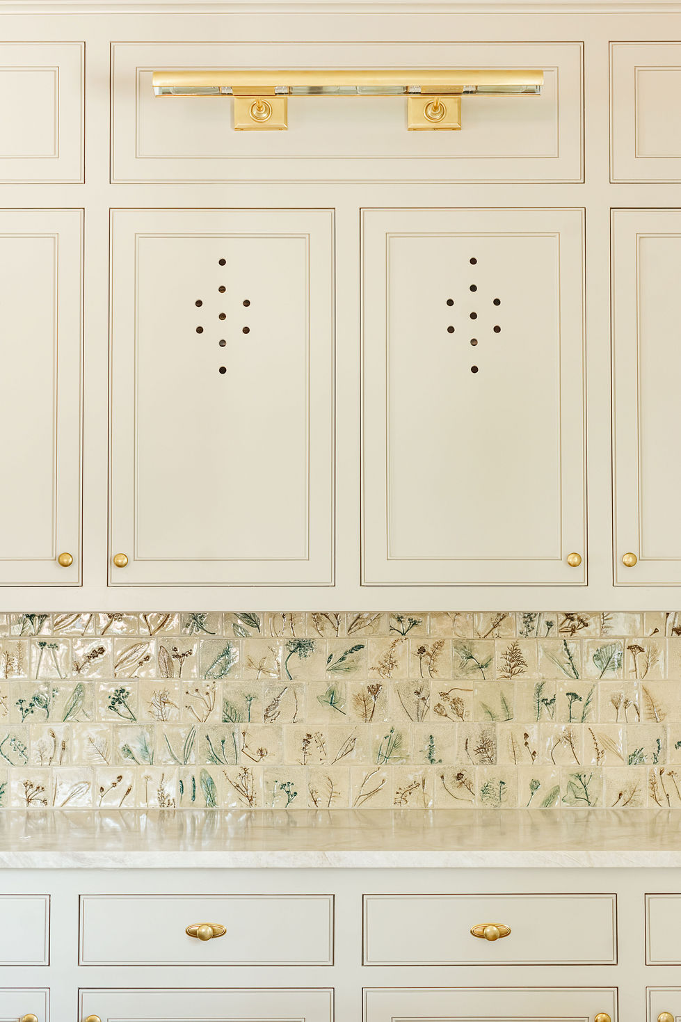 White cabinets with decorative perforations and patterned backsplash.