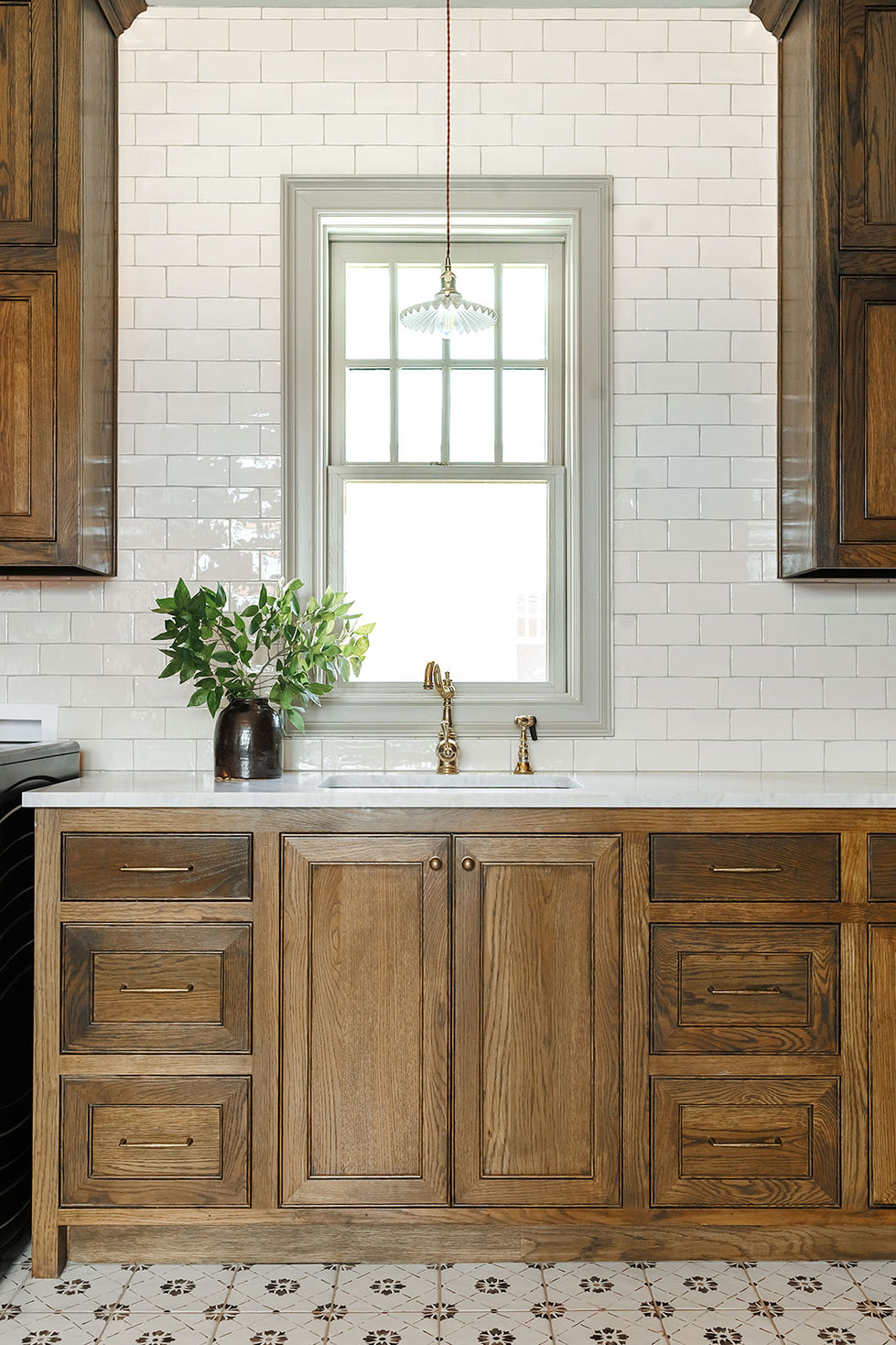 Rustic kitchen with wooden cabinets and white backsplash.