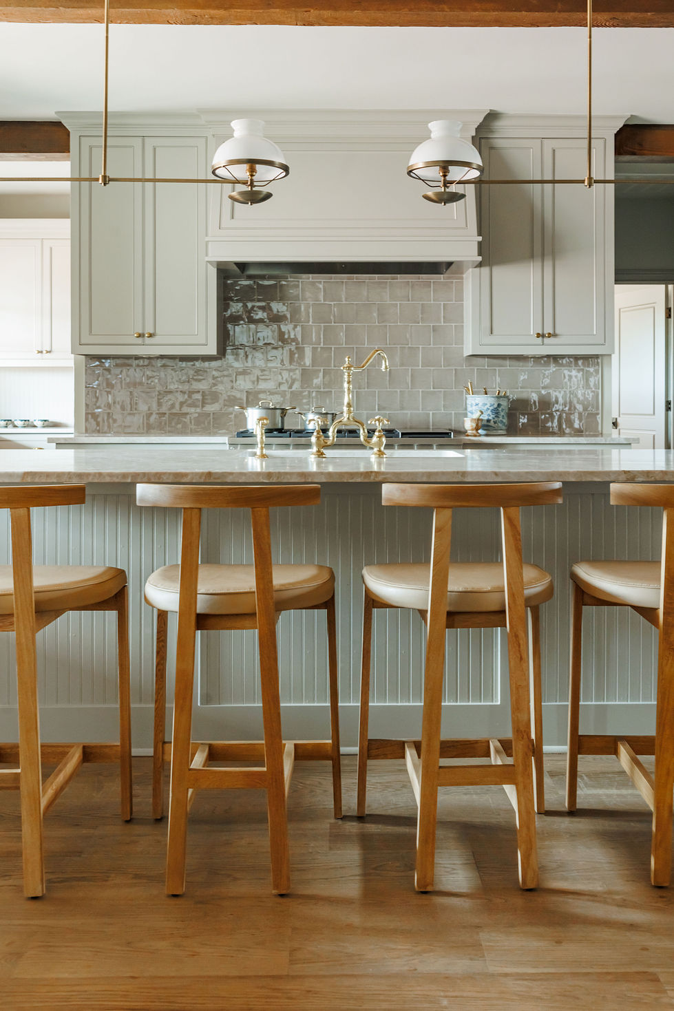Modern kitchen with wooden stools and elegant lighting.