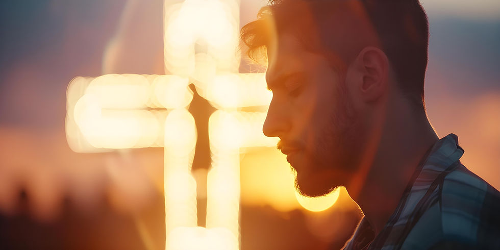 Young man in profile prays with eyes closed beside a glowing cross at sunset, warm light and a contemplative mood.