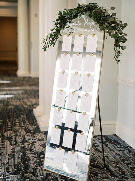 Mirrored seating chart with wax seals and floral garland