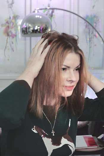 Woman with brown hair adjusting her hair