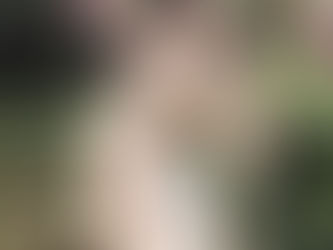 girl with long blonde balayage coloured hair looking down in a garden with green and pink in the background