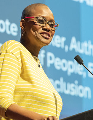 Keynote speaker Lachandra B. Baker, founder of LBB Edutainment, delivers a powerful corporate culture presentation on stage at a professional leadership event.