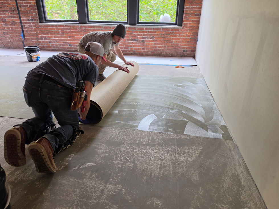 Marmoleum installers rolling material into freshly applied adhesive. Work completed by Linoleum Pros, Forbo Certified Installers.