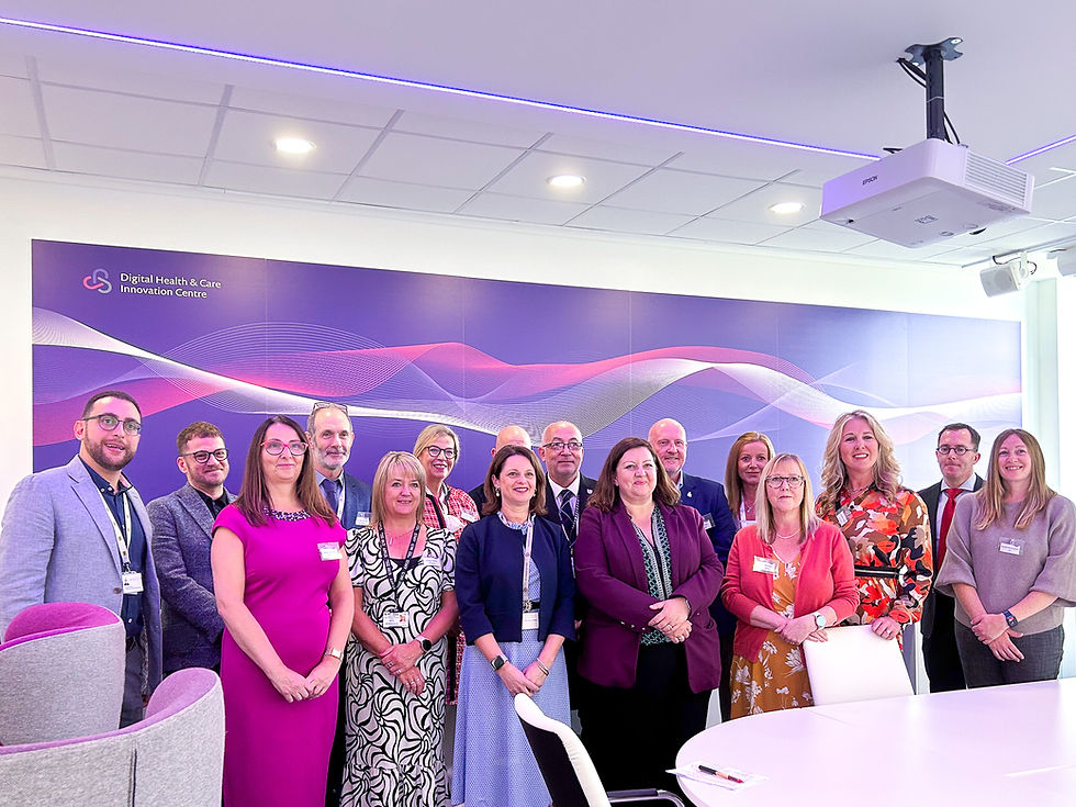 Fifteen people in business attire pose together in a conference room with the Digital Health & Care Innovation Centre logo and wave design in the background.