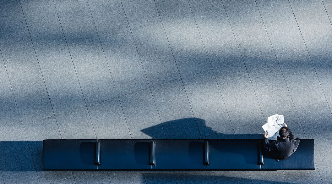 Vista aérea de una silueta sentada en un banco frente a una arquitectura depurada – expertise marketing hospitalidad, el recorrido digital como experiencia del cliente – Patrimonio Hospitality