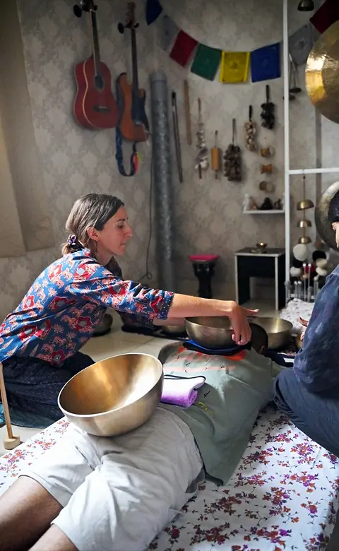 A student practising a sound healing session with singing bowls over a client during hands-on training at Ananda Dhwani.