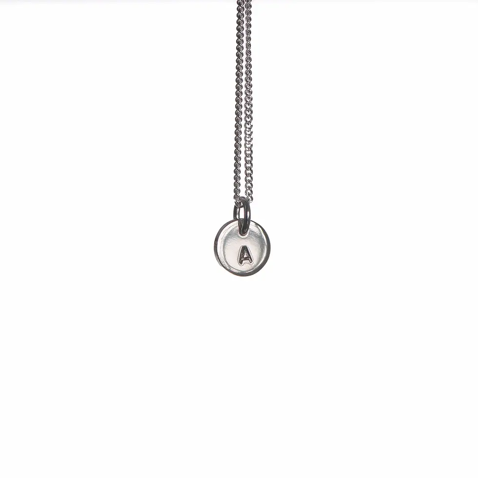 Tiny Initial Necklace in hammered silver showing stamped initial side on a white background