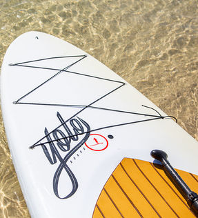 white paddle board with paddle floating in shallow Gulf waters