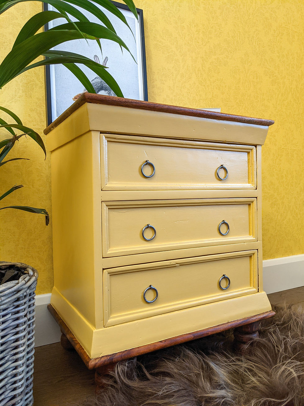 Small teak chest of drawers painted in yellow and featuring exposed wood on the top