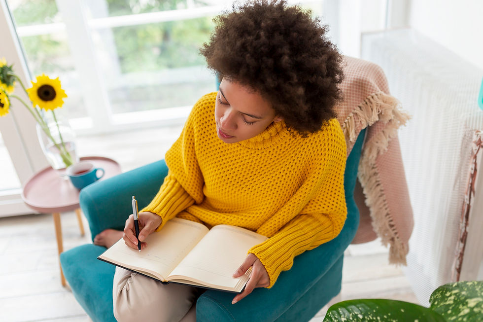 young woman writing daily affirmations in journal; self care