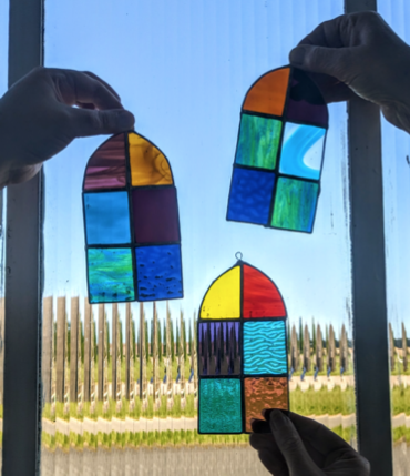 Three foiled glass panels being held up in front of a blue sky background