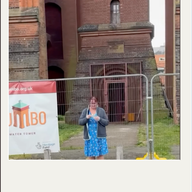 person sewing in front of a giant water tower with a banner next to them and 'Jumbo' on the banner