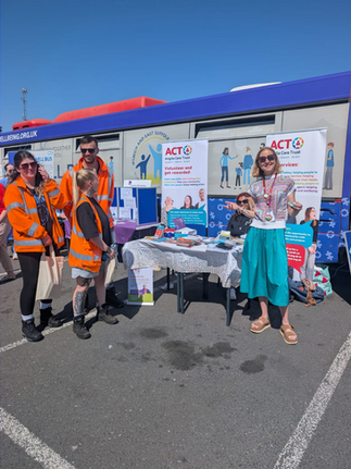 Members of ACT in front of the Be Well Bus with banners and literature