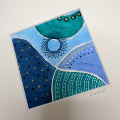 Fluid pattern piece of artwork in blue, green and white with gold embellishments and a stitched spiral-style star embroidered on it. The picture is in a white mount with a signature on it