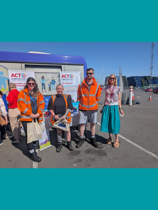 Members of ACT in front of the Be Well Bus with banners and literature