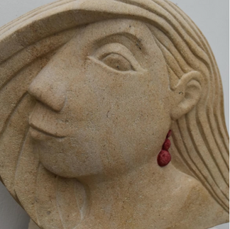 Carved stone bust of a woman with long hair and red earrings, in a stylised abstract design.