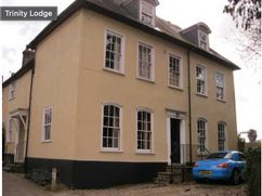 Large house with 5 first floor windows, four ground floor windows and door with two roof windows. There is a blue car to the front of the building