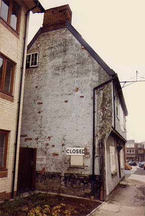 Side elevation of a house with a closed sign on the wall. Image is a historic record