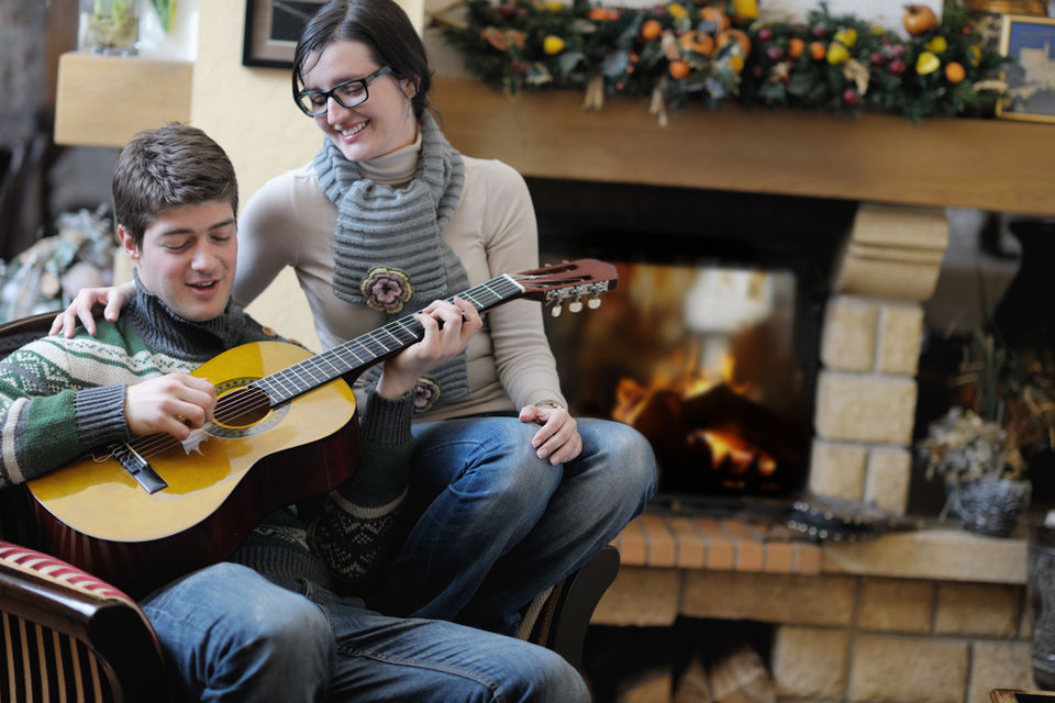 young-romantic-couple-sitting-and-relaxing-in-front-of-fireplace-at-home-SBI-300818276.jpg