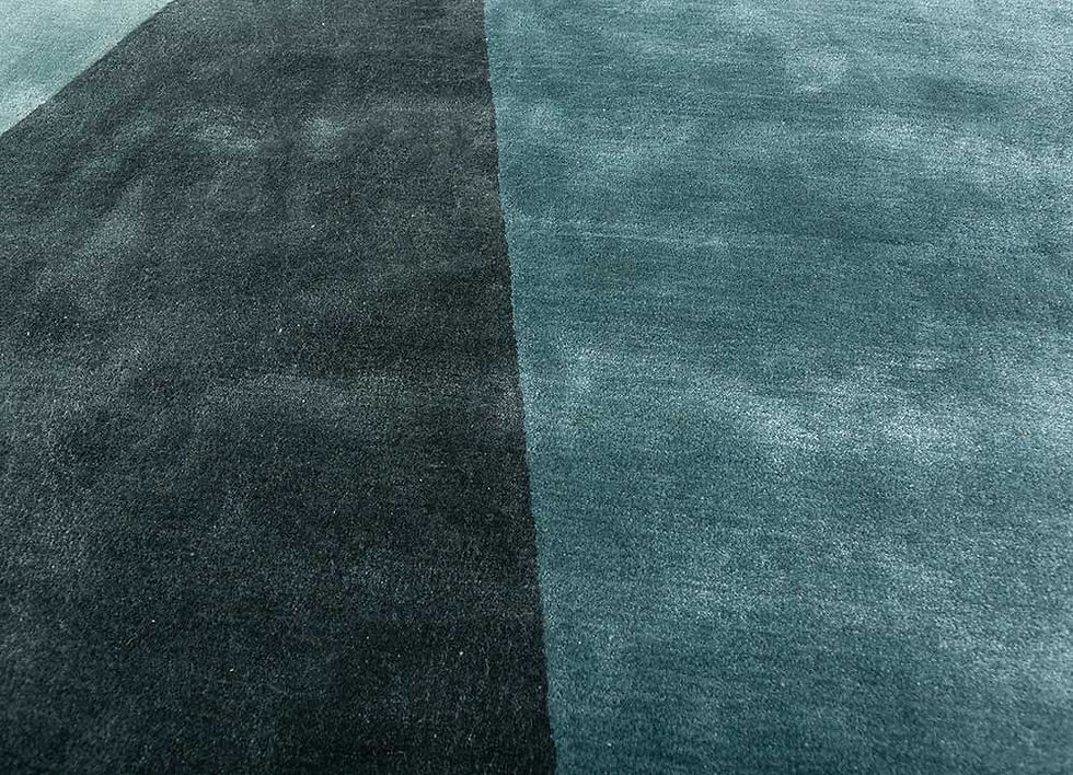 Close-up of adjoining dark charcoal green and teal geometric sections, showing fine pile texture and soft tonal shading.