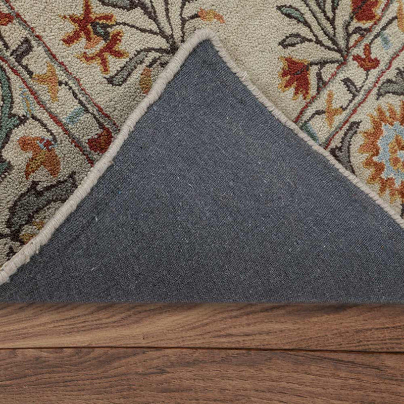 Thumbnail: Folded corner of an ivory floral rug revealing grey fabric backing and pale edge binding on wooden flooring.