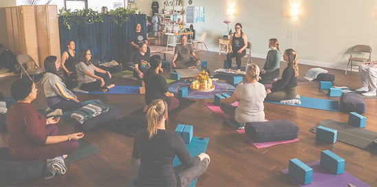Yoga students sitting on mats, bolsters, and chairs in a circle at Zia Yoga