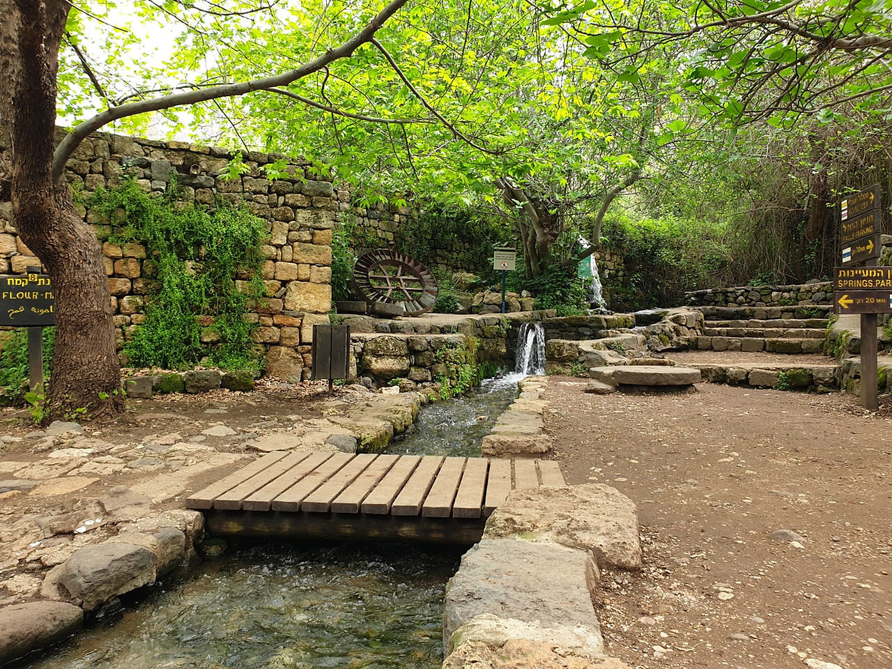 A small wooden bridge crossing a man-made water channel among the ruins of an ancient flour mill in Banias.