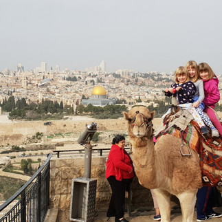 Family on a camel ride at the Mount of Olives overlooking the Old City of Jerusalem and the Dome of the Rock.