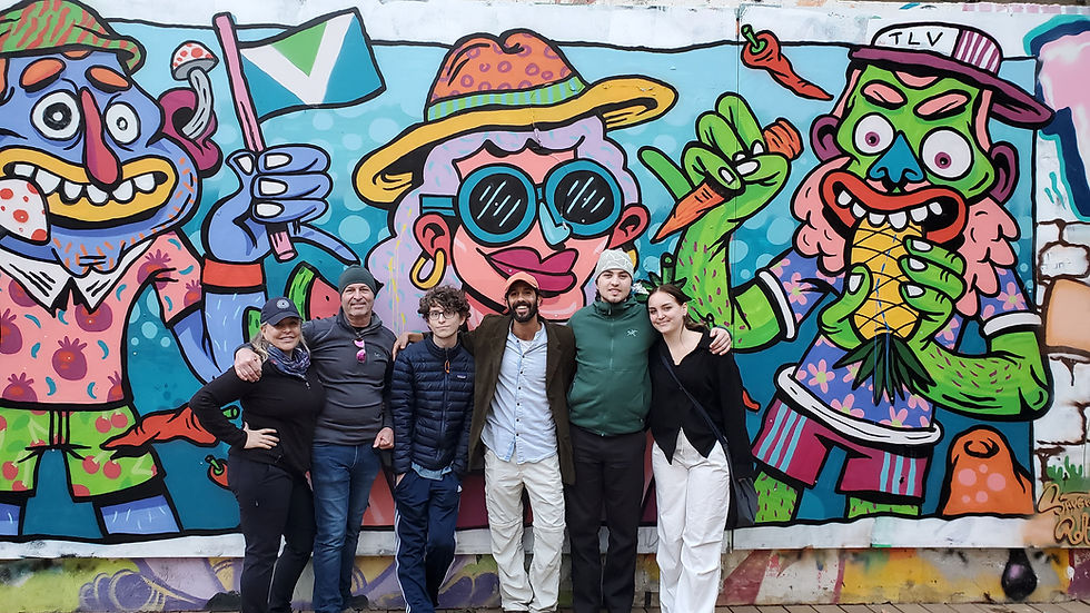 Sagi Levy private tour group posing in front of colorful Tel Aviv street art mural.
