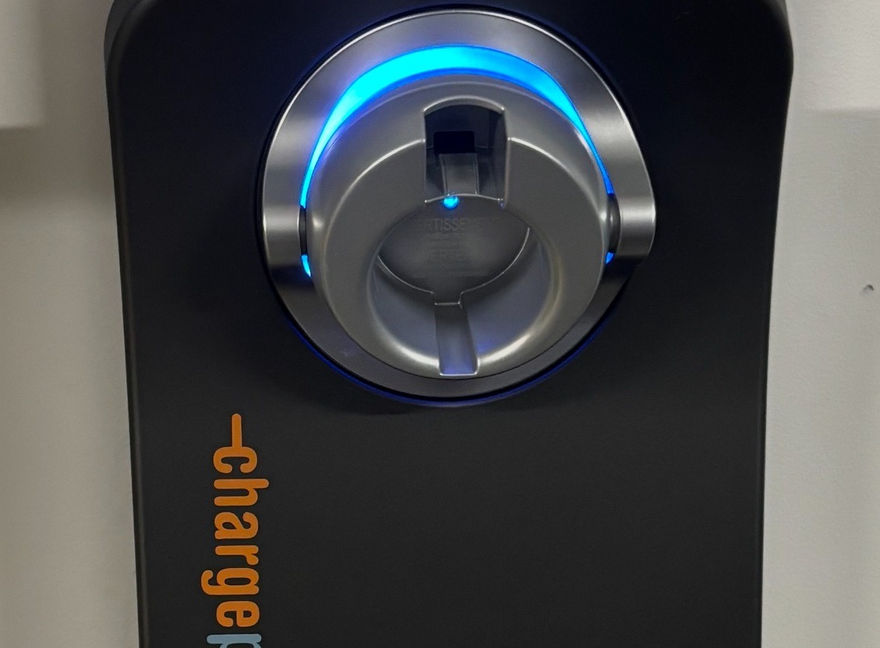 ChargePoint+ EV charger with blue light and text on black background.