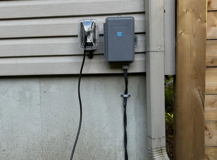 Boîtier électrique extérieur installé sur un mur, fil noir et tuyau. LMBC ÉLECTRIQUE