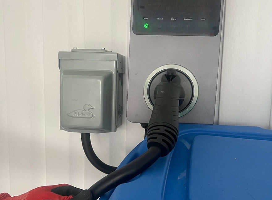 Une prise électrique avec un câble branché, affichant un témoin lumineux.