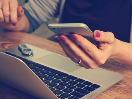 A woman sitting at a desk with a laptop and smartphone