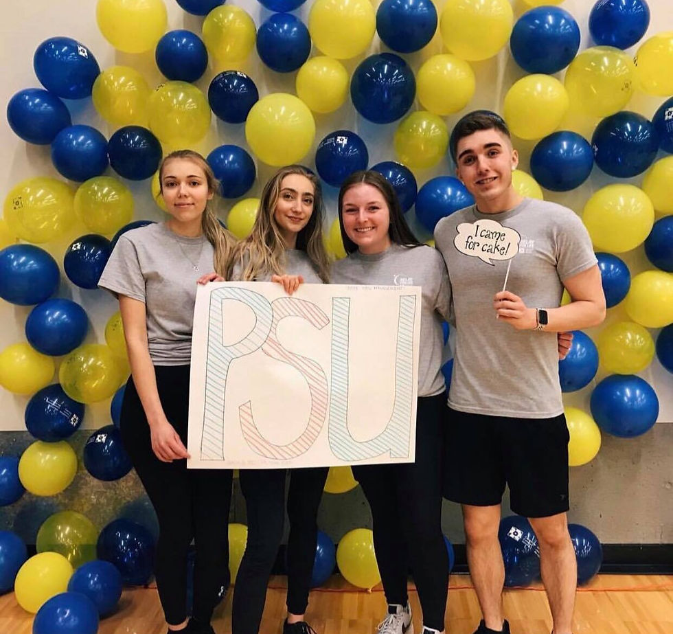 Our executive team in front of a wall of blue and yellow balloons, with a sign that says "PSU"