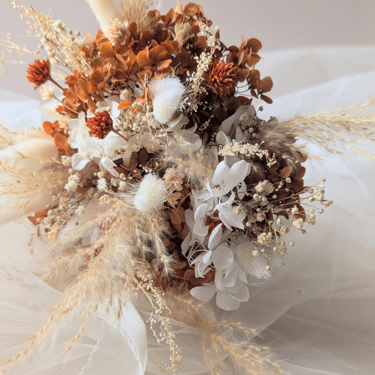 Bouquet de mariée en fleurs séchées dans des tons terracotta et blanc pour un mariage